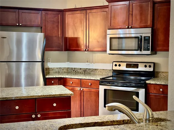 a kitchen with granite countertop a stove top oven microwave and cabinets