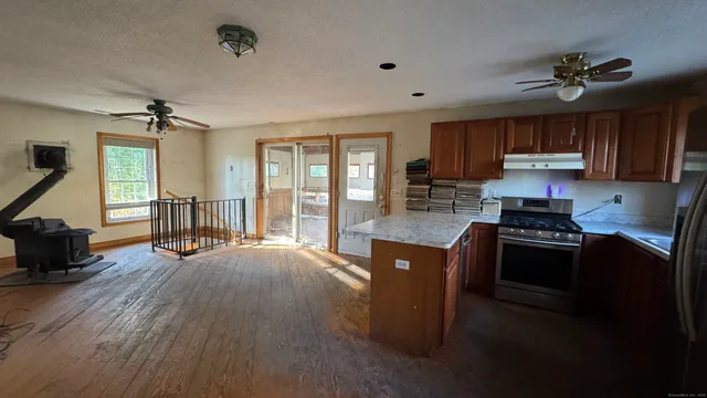 a kitchen with stainless steel appliances granite countertop a stove top oven a sink with wooden cabinets and glass door