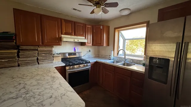 a kitchen with stainless steel appliances granite countertop a refrigerator a sink dishwasher a stove and white countertops with wooden floor