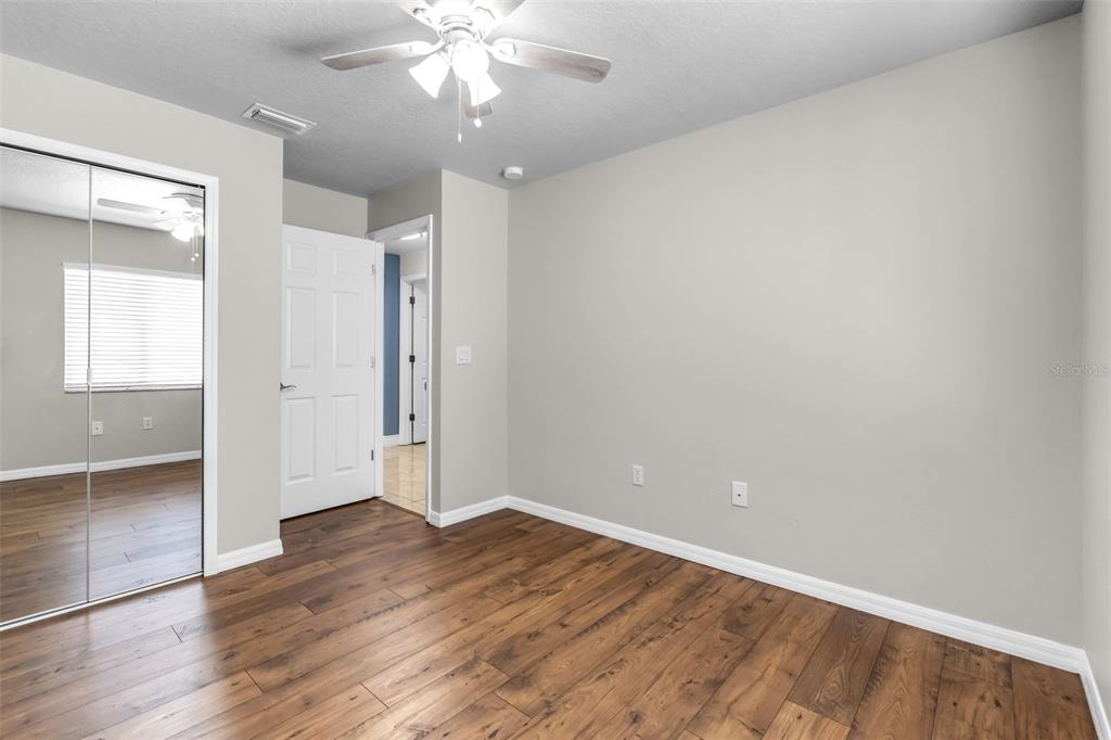 1424 Ocean Reef Road Wesley Chapel, FL 33544 - Photo 19 of 47 an empty room with wooden floor and windows