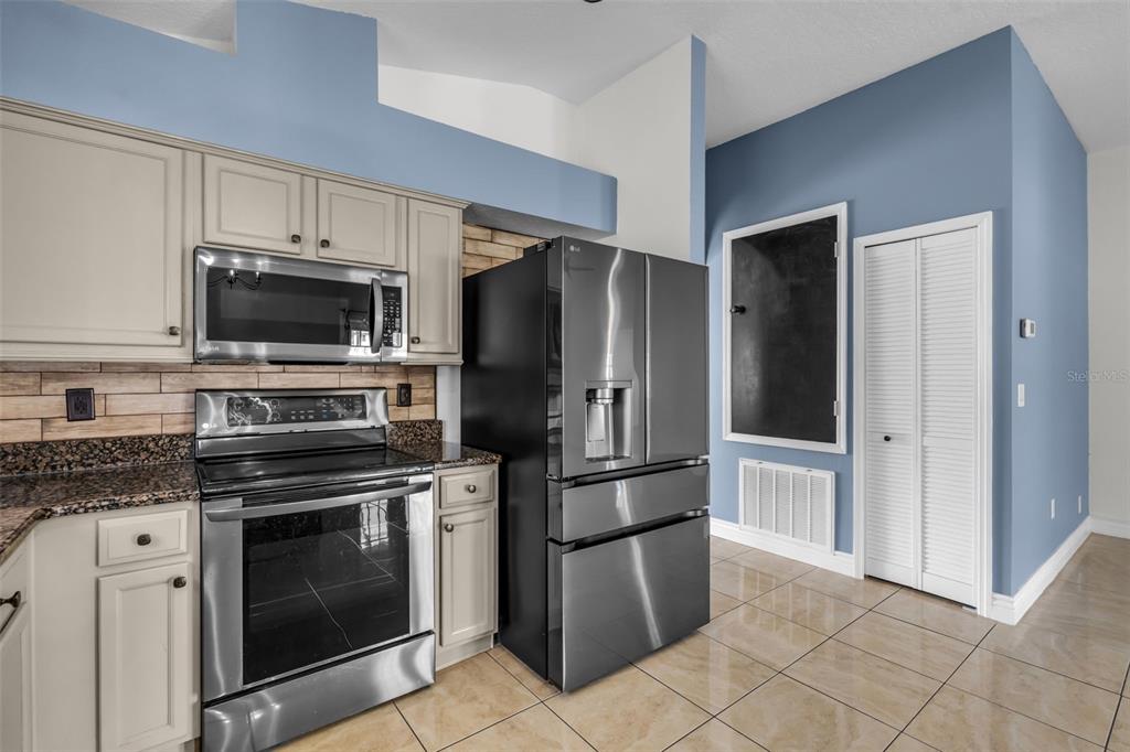 1424 Ocean Reef Road Wesley Chapel, FL 33544 - Photo 10 of 47 a kitchen with appliances a refrigerator and a stove top oven