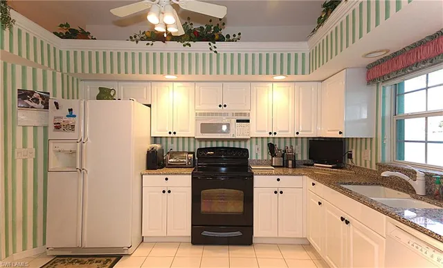 a kitchen with granite countertop a refrigerator stove and sink