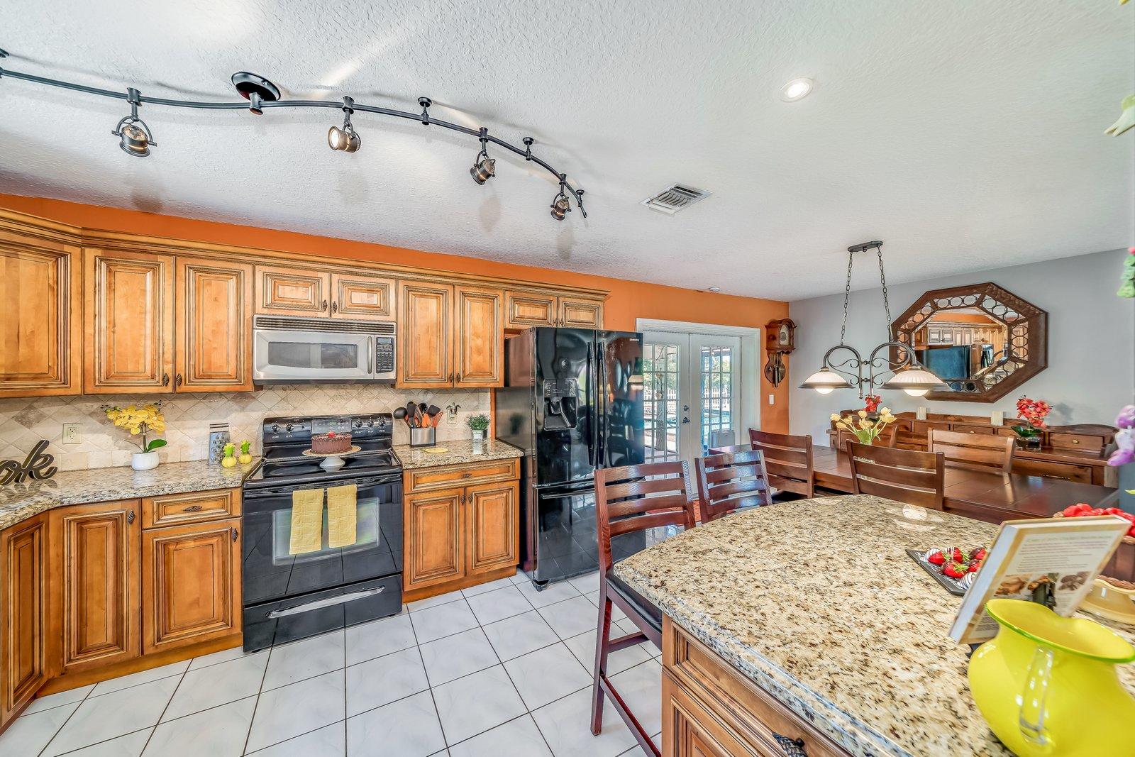 22206 Aquila Street Boca Raton, FL 33428 - Photo 20 of 73 a kitchen with stainless steel appliances granite countertop a stove top oven a sink dishwasher and cabinets with wooden floor