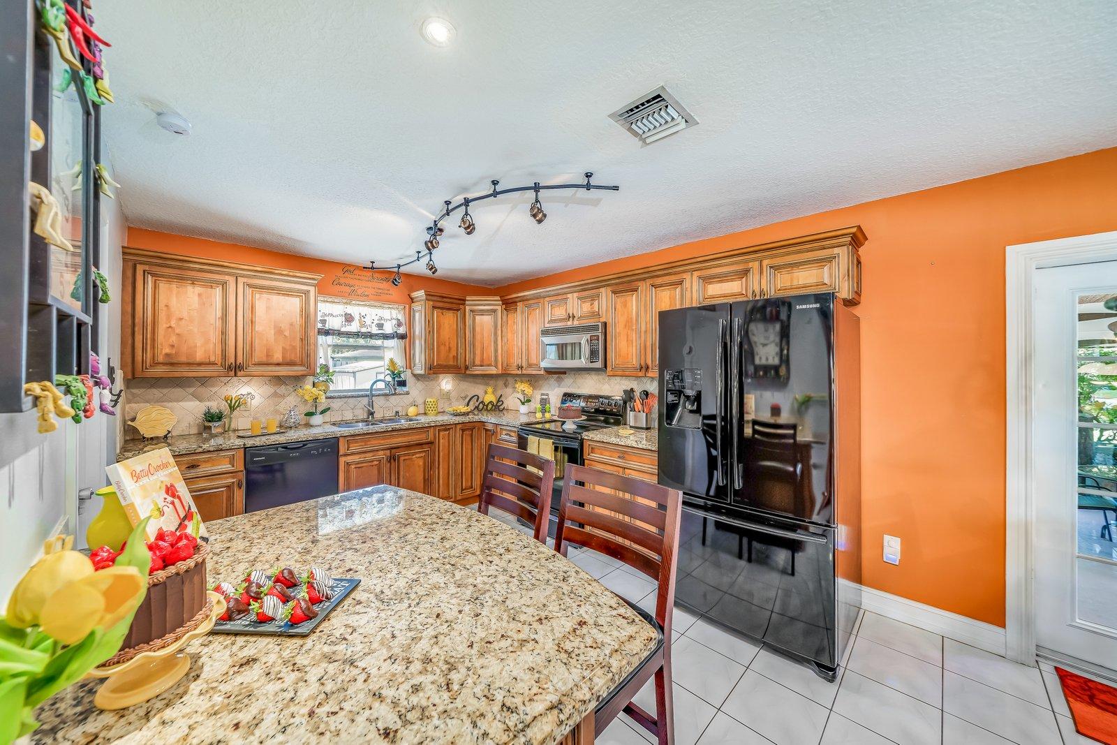 22206 Aquila Street Boca Raton, FL 33428 - Photo 21 of 73 a kitchen with stainless steel appliances kitchen island granite countertop a refrigerator and stove top oven