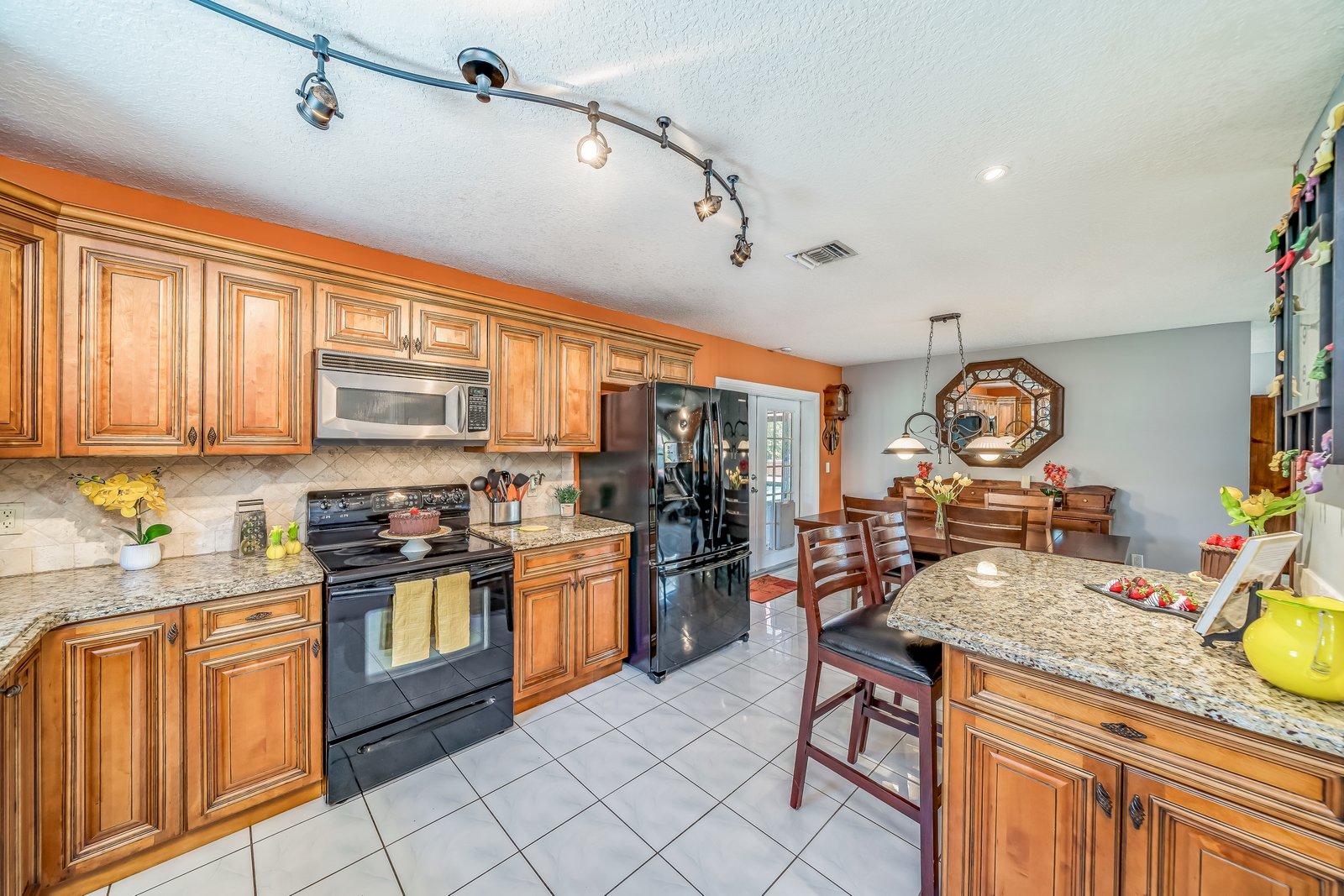 22206 Aquila Street Boca Raton, FL 33428 - Photo 23 of 73 a kitchen with stainless steel appliances granite countertop a stove top oven a sink dishwasher and cabinets with wooden floor