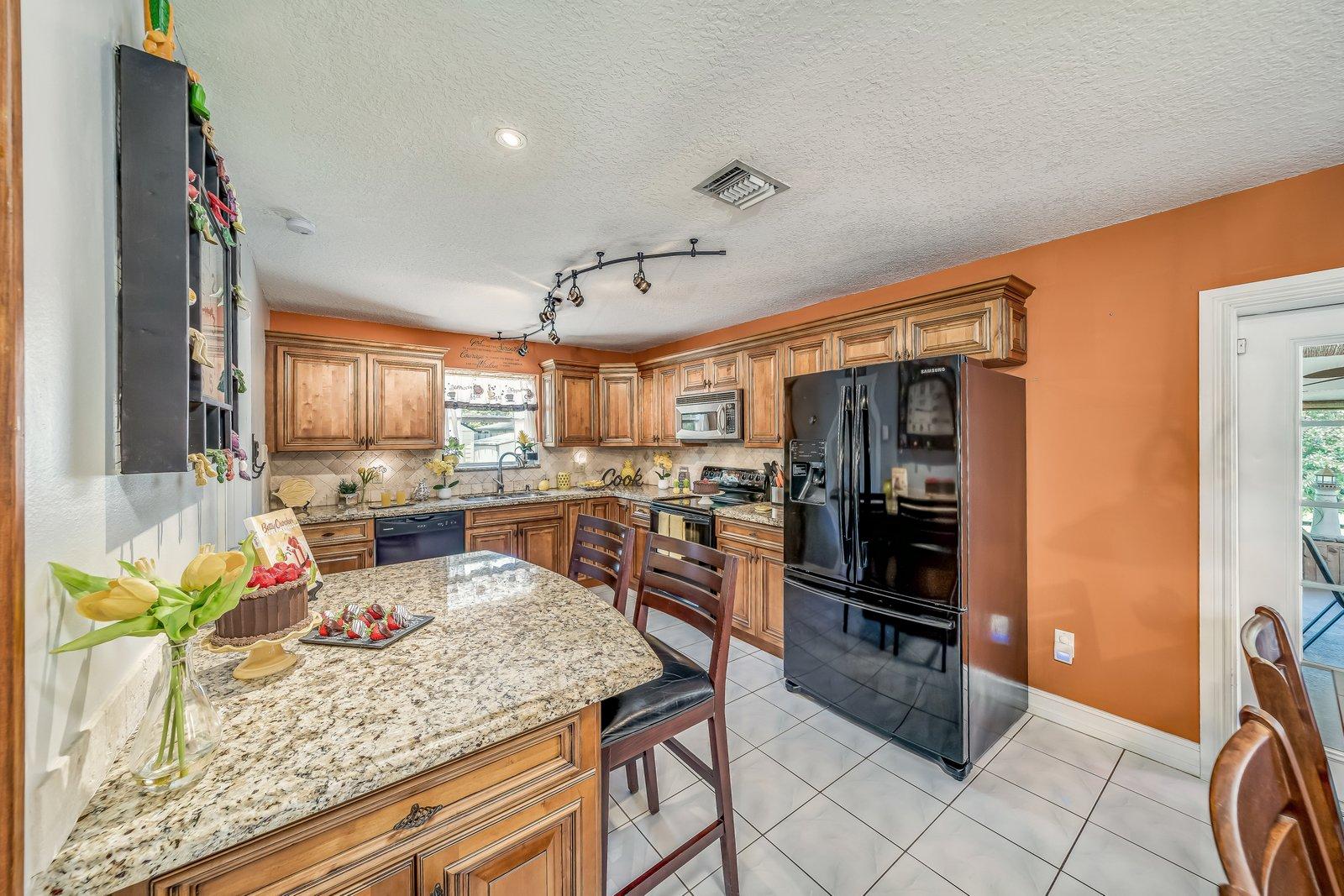 22206 Aquila Street Boca Raton, FL 33428 - Photo 27 of 73 a kitchen with stainless steel appliances kitchen island granite countertop a refrigerator and stove