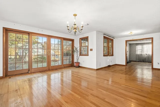 a view of an empty room with window and wooden floor