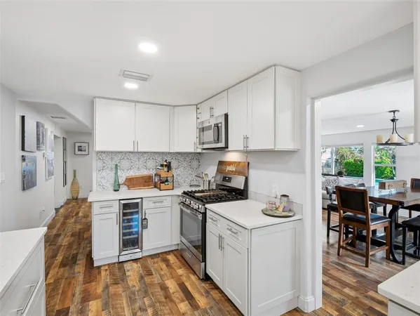 a kitchen with granite countertop a stove top oven a sink dishwasher a dining table and chairs with wooden floor