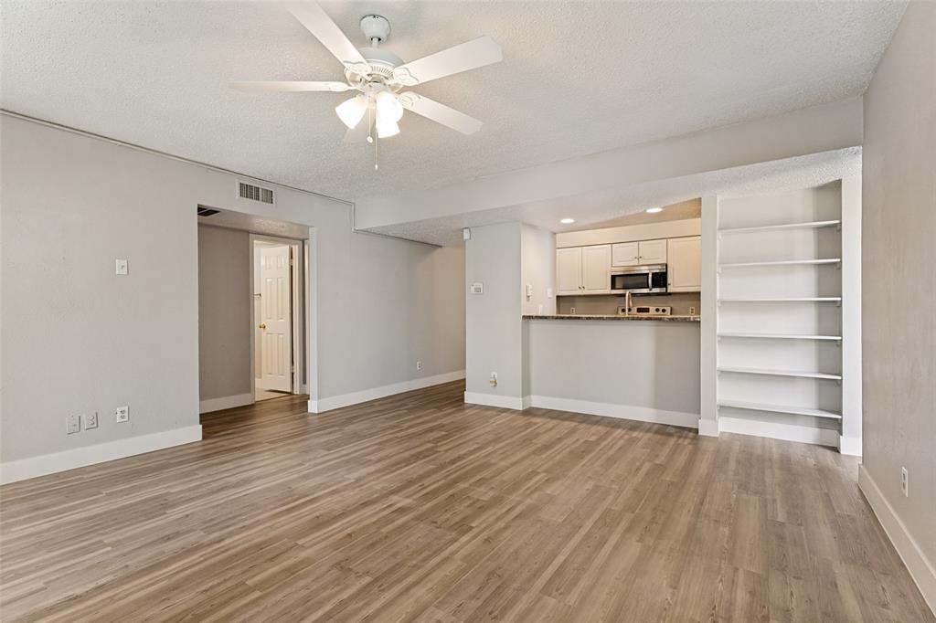 5522 Boca Raton Boulevard, Unit 404 Fort Worth, TX 76112 - Photo 7 of 12 Open-concept living area with wood-finish flooring, a ceiling fan, and built-in shelving