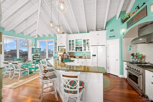 a kitchen with stainless steel appliances granite countertop a stove a refrigerator a sink and a dining table with wooden floor