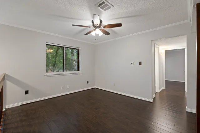 an empty room with wooden floor chandelier fan and windows