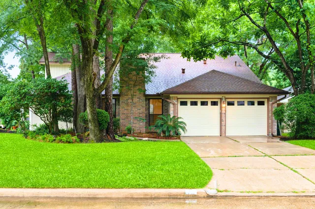 a view of a white house with a big yard and large trees