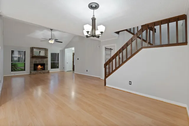 a view of an empty room with wooden floor and stairs