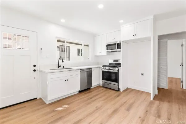 a large white kitchen with stainless steel appliances granite countertop a stove a sink and white cabinets