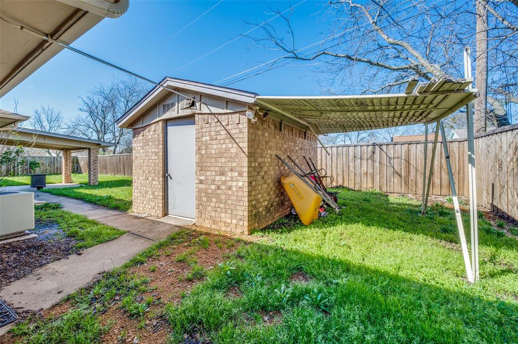508 South Pedigo Street Pilot Point, TX 76258 - Photo 26 of 26 Brick storage shed with a gabled roofline and an attached metal awning
