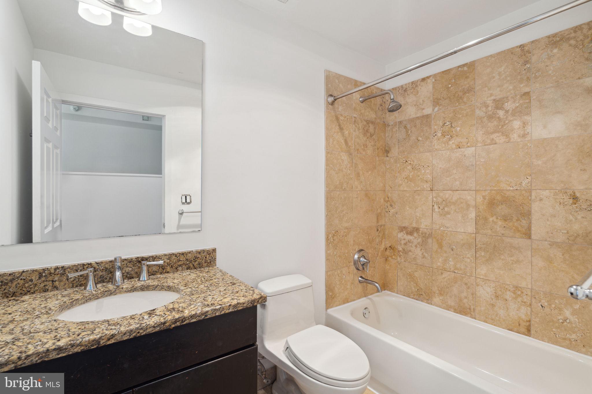 22 South Front Street, Unit 304 Philadelphia, PA 19106 - Photo 10 of 20 a bathroom with a granite countertop sink toilet mirror and bathtub