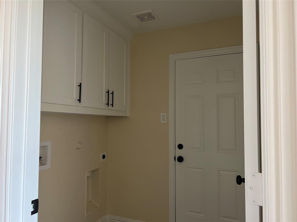 8008 County Road 1058 Rice, TX 75155 - Photo 10 of 25 Laundry area featuring white shaker-style cabinetry with matte black hardware, a four-panel door with black hardware, and an overhead ventilation fan