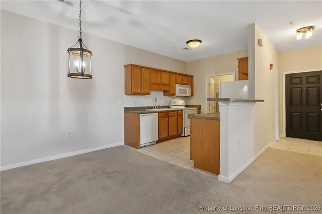 a kitchen with stainless steel appliances granite countertop a stove a refrigerator a sink dishwasher and white cabinets with wooden floor