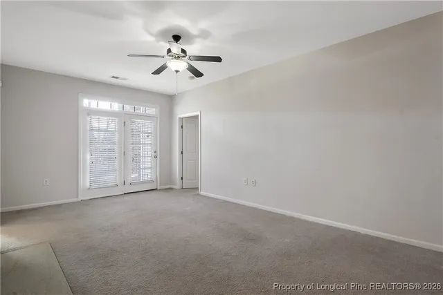 a view of an empty room with chandelier fan and fire place