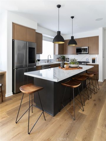 a kitchen with stainless steel appliances kitchen island granite countertop a sink a stove and a wooden floors