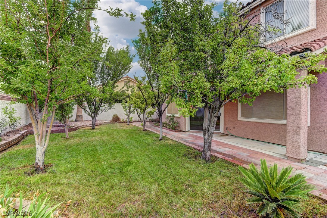 1813 Snow Spring Lane Las Vegas, NV 89134 - Photo 33 of 37 A verdant backyard retreat features lush green grass and mature trees, creating a private outdoor sanctuary.