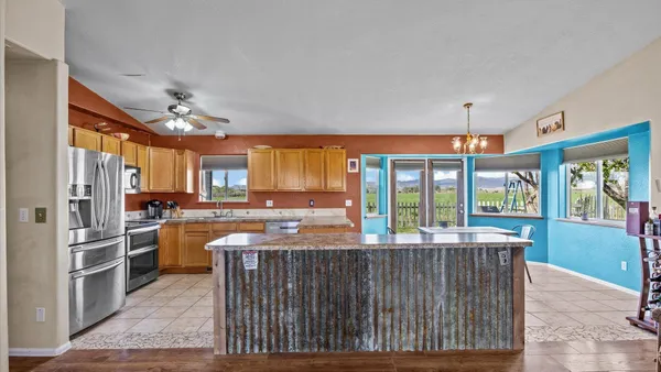 a kitchen with stainless steel appliances granite countertop a refrigerator a sink dishwasher a stove and a dining table with wooden floor