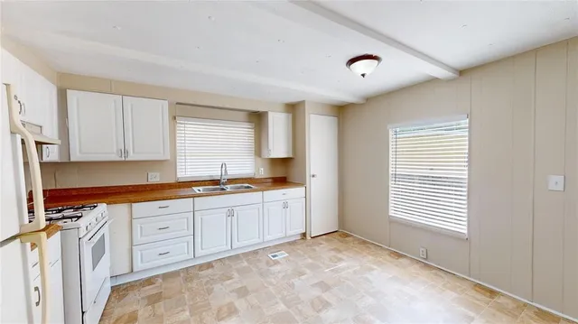 a large kitchen with granite countertop a sink and white cabinets