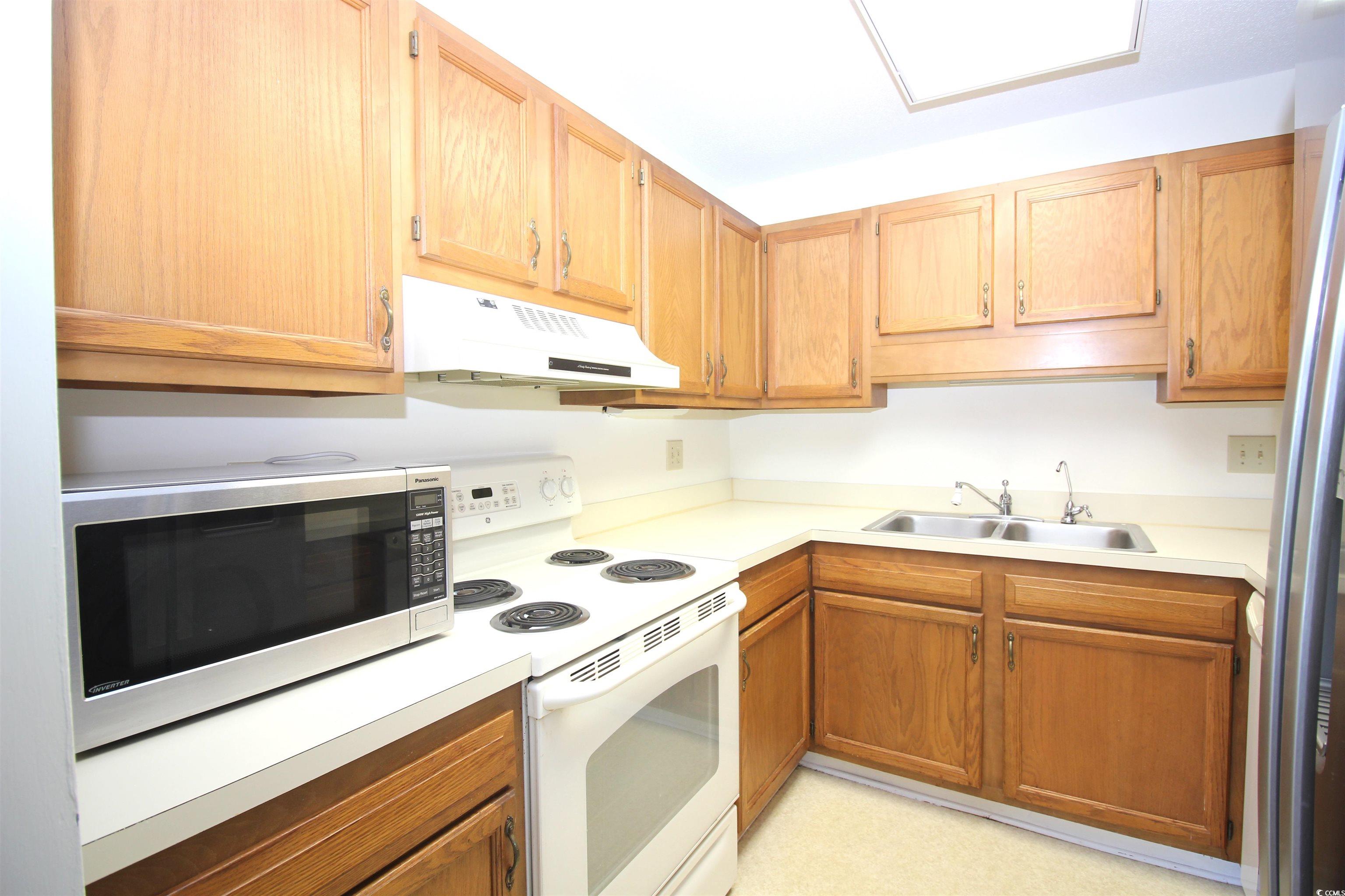 5001 Little River Road, Unit E509 Myrtle Beach, SC 29577 - Photo 8 of 30 Kitchen with white electric range, under cabinet range hood, light countertops, and freestanding refrigerator