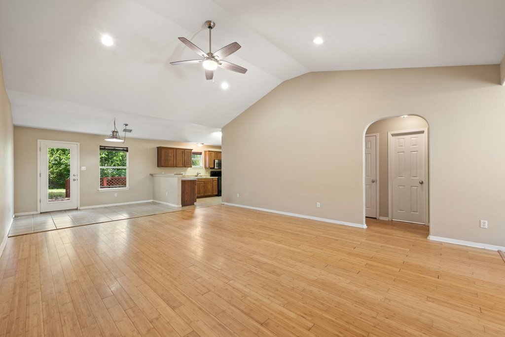 5208 Sioux Lane Austin, TX 78734 - Photo 16 of 35 A spacious common area boasts warm wood flooring and a modern ceiling fan, seamlessly connecting to the kitchen.