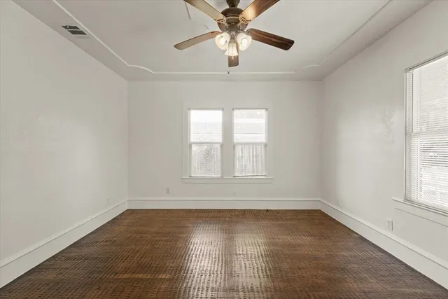 an empty room with a window and a fan
