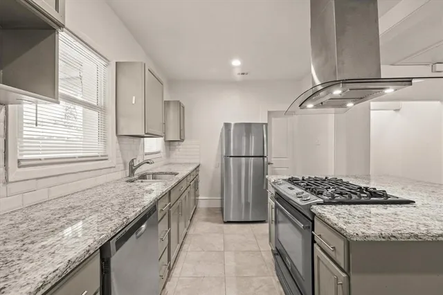 a kitchen with granite countertop kitchen island stainless steel appliances a refrigerator a sink and a stove