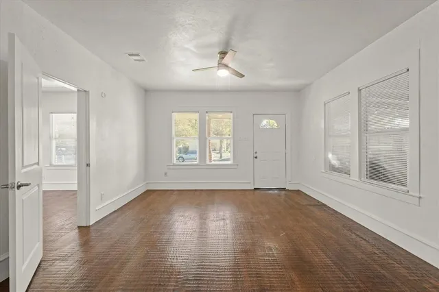 an empty room with wooden floor and windows
