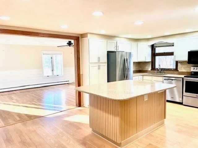 a kitchen with stainless steel appliances kitchen island granite countertop a refrigerator a stove and a sink with granite countertops