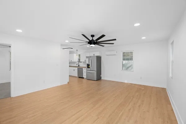 a view of a livingroom with a ceiling fan & windows