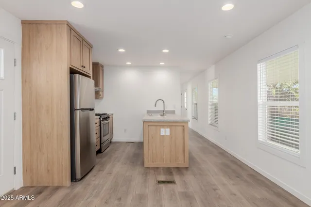 a kitchen with stainless steel appliances granite countertop a refrigerator a sink dishwasher and a stove with wooden floor