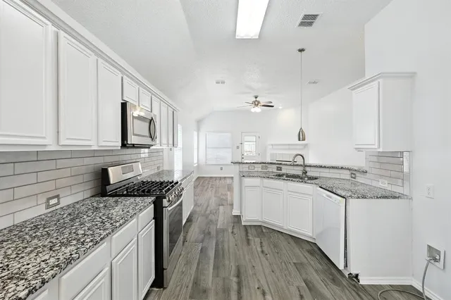 a kitchen with granite countertop cabinets stainless steel appliances a sink and a counter space