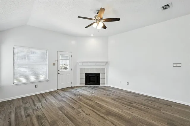 wooden floor fireplace and windows in an empty room