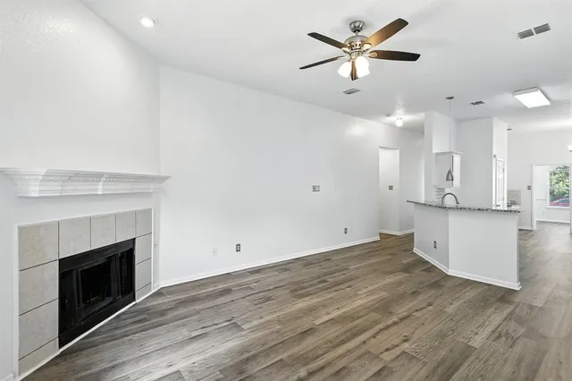 a view of an empty room with kitchen and fireplace