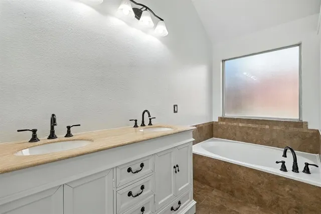 a bathroom with a tub a sink and mirror