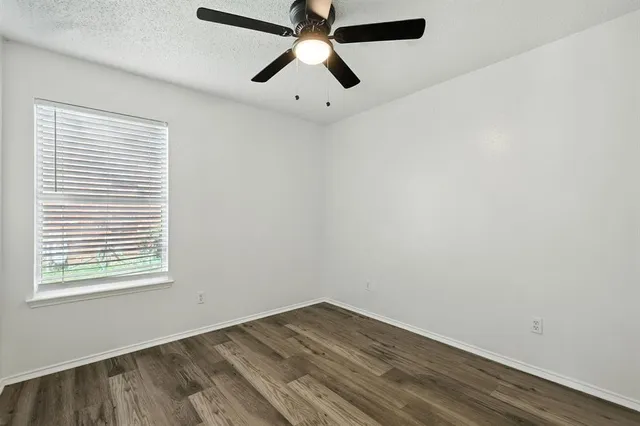 an empty room with a window and a ceiling fan