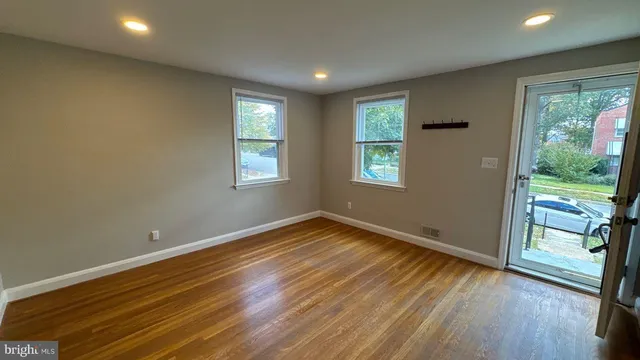 a view of an empty room with glass door and wooden floor