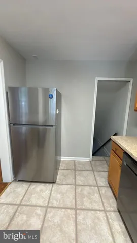 a view of a refrigerator in kitchen and an empty room