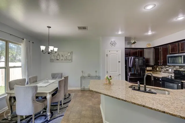 a kitchen with stainless steel appliances kitchen island granite countertop a sink refrigerator and cabinets