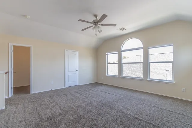 an empty room with windows and ceiling fan