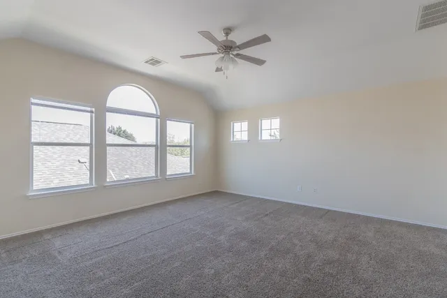 an empty room with windows and fan