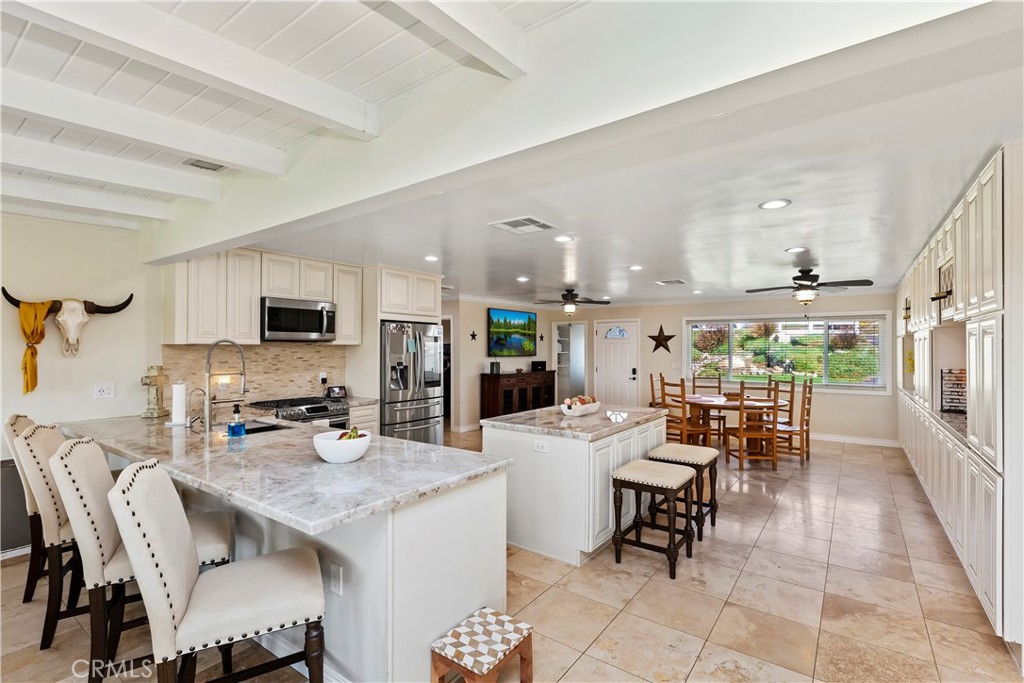 a kitchen with stainless steel appliances kitchen island granite countertop a table chairs and a refrigerator