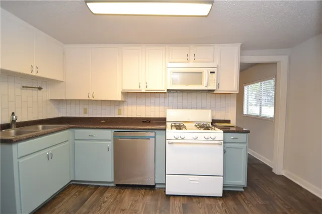 a kitchen with a stove white cabinets and wooden floor
