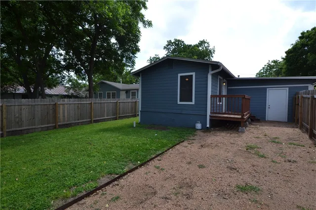 a view of a backyard with wooden fence and a large tree
