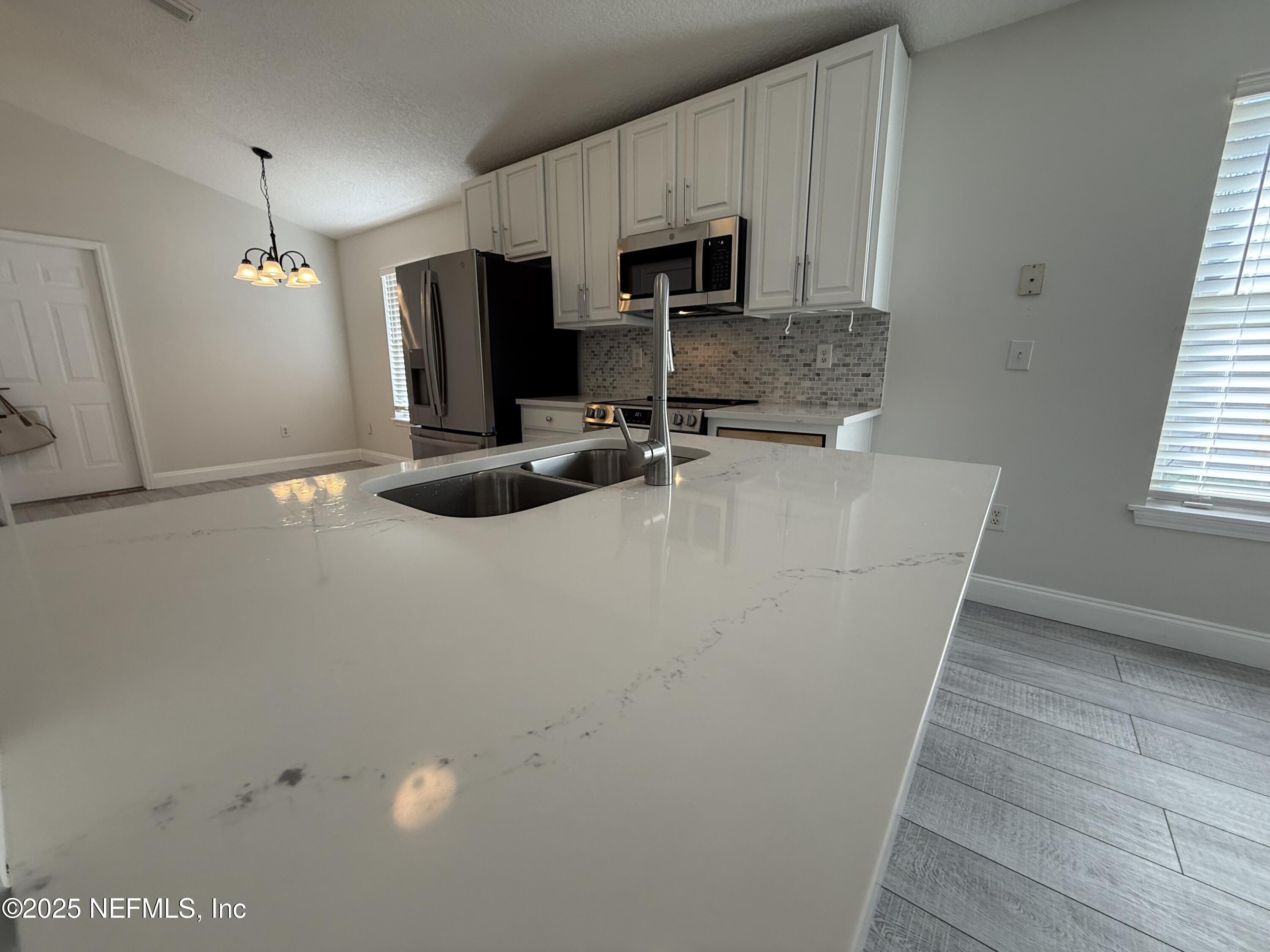 677 MacKenzie Circle St. Augustine, FL 32092 - Photo 11 of 92 a kitchen with a sink a microwave a refrigerator and cabinets
