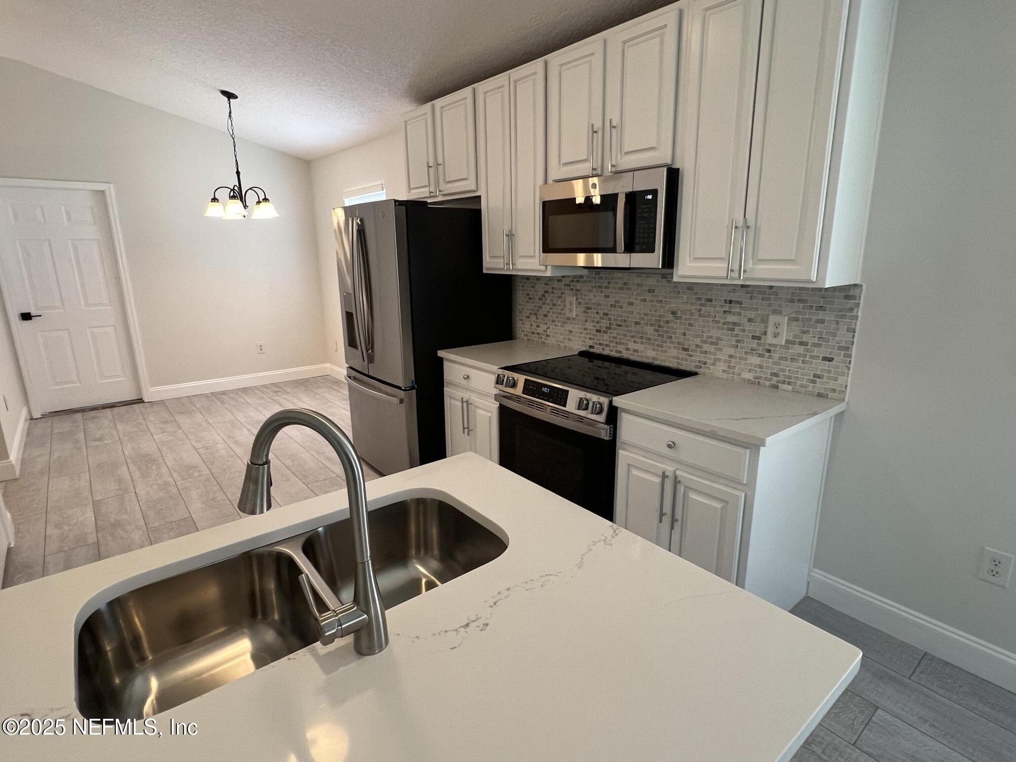 677 MacKenzie Circle St. Augustine, FL 32092 - Photo 14 of 92 a kitchen with granite countertop a sink a stove a refrigerator and cabinets